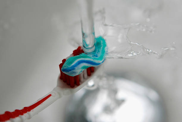 toothbrush under a faucet with toothpaste