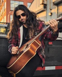 Musician Bryan Ruby wearing sunglasses and playing guitar