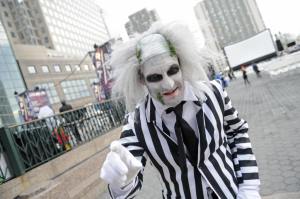 A close up of a man dressed as Beetljuice wearing the black and white suit and make up with a wig